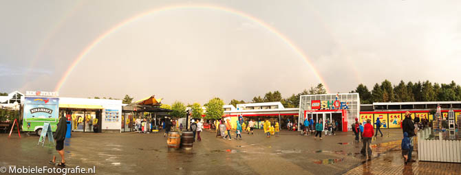 Panoramafoto van Legoland in Denemarken, met een regenboog. De persoon die linksonder loopt is op de foto hieronder uitvergroot weergegeven.